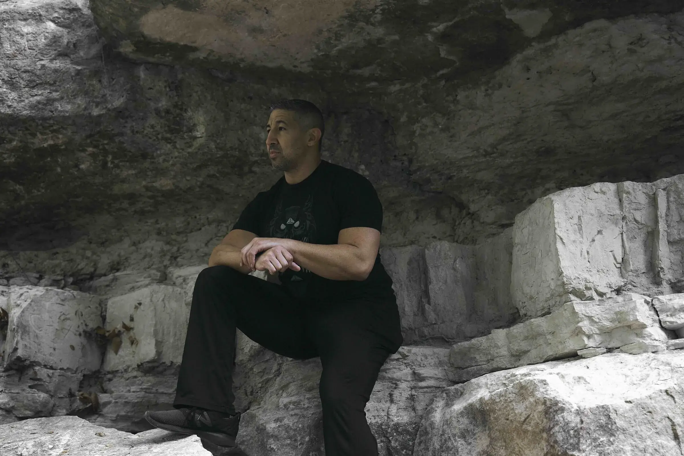 John Wolf seated in a Hill Country limestone alcove